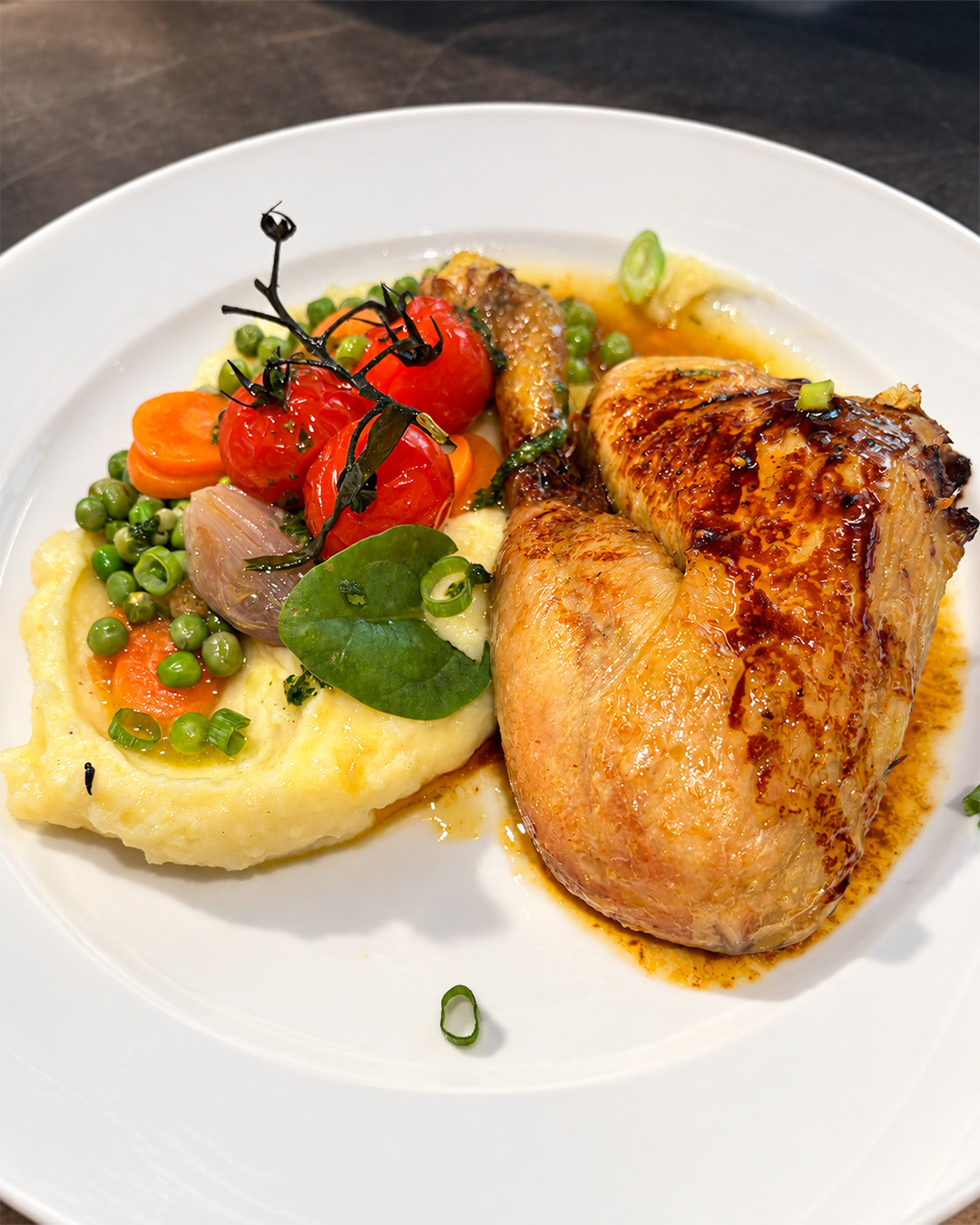 Volaille rôtie servie avec purée, petits pois, carottes et tomates