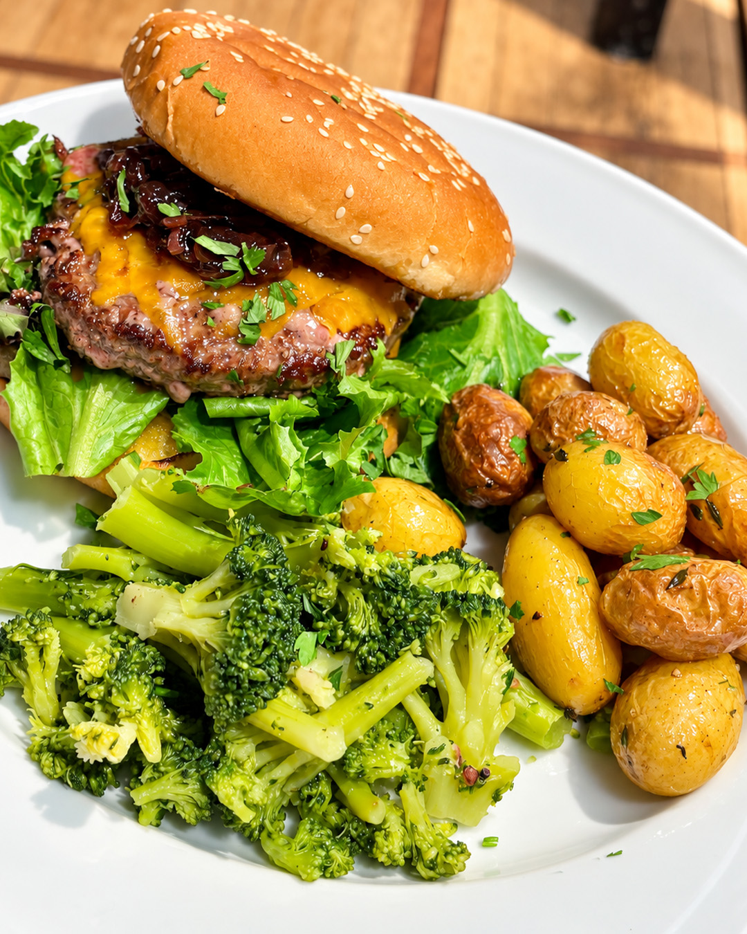 Burger servi avec pommes de terre rôties, brocolis et salade verte
